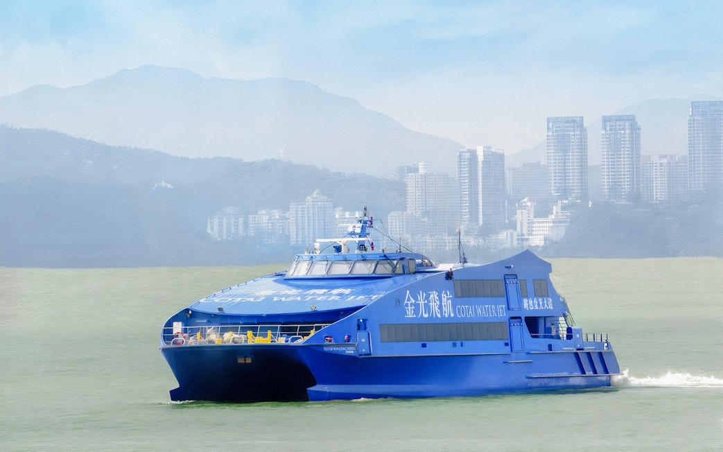 Cotai Water Jet ferry traveling between Hong Kong Island and Macau with city skyline in background.