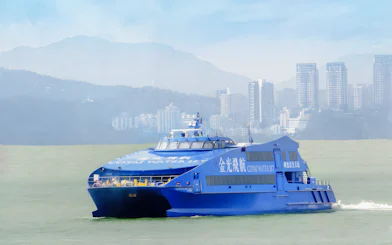 Cotai Water Jet ferry traveling between Hong Kong Island and Macau with city skyline in background.
