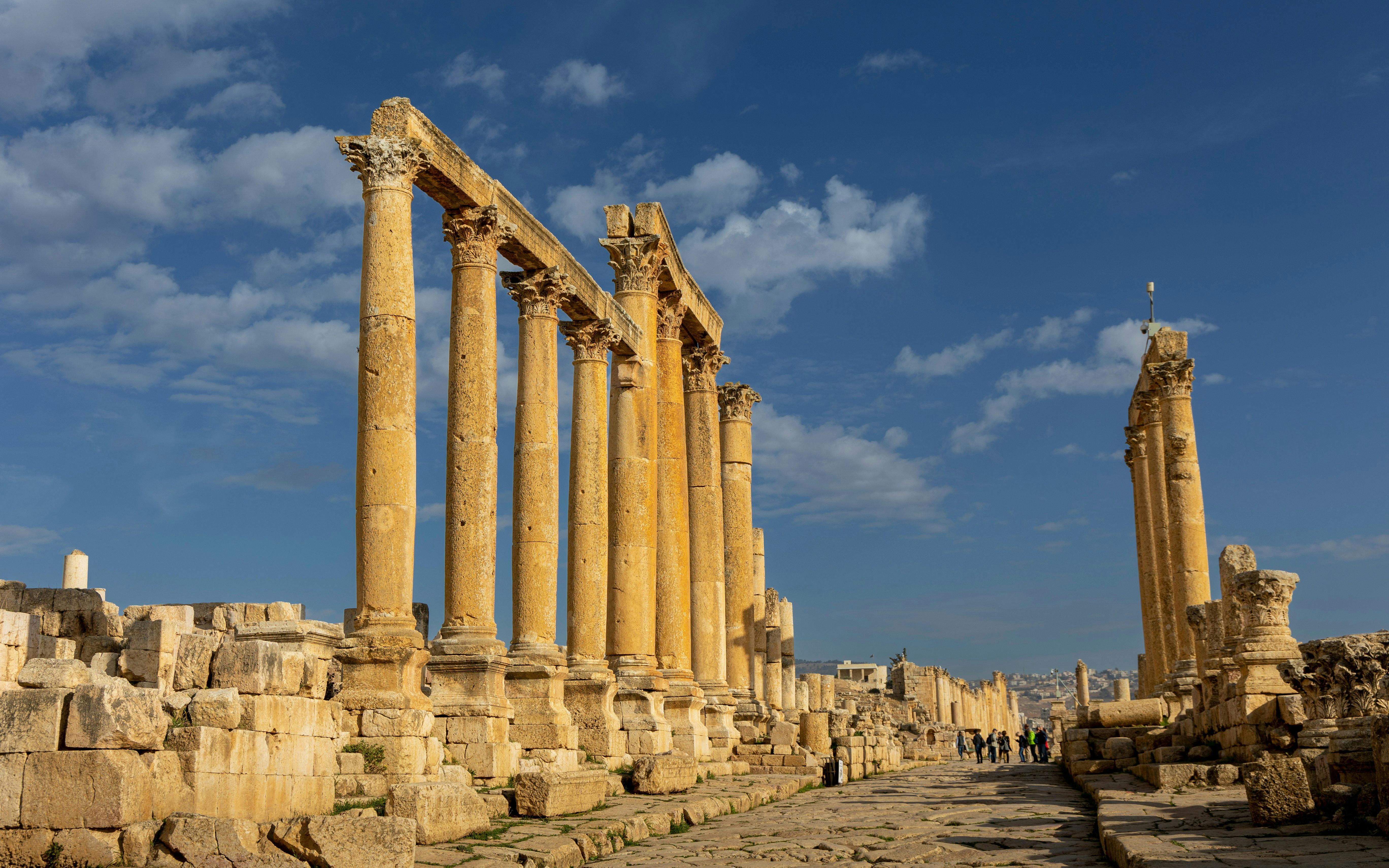 Ancient Roman columns at Jerash ruins in Oman under a blue sky.