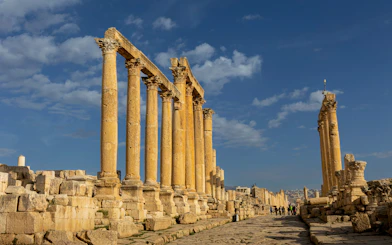 Ancient Roman columns at Jerash ruins in Oman under a blue sky.