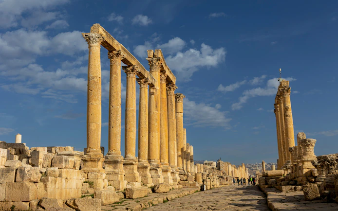 Ancient Roman columns at Jerash ruins in Oman under a blue sky.