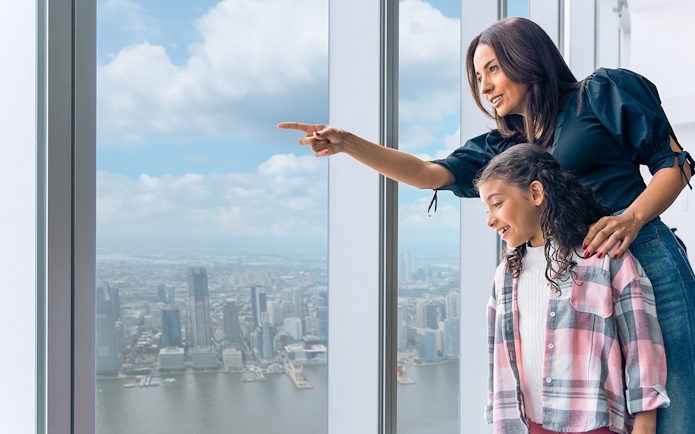 Tourists enjoying New York City skyline from One World Observatory's 100th-floor deck.