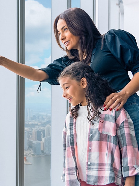 Tourists enjoying New York City skyline from One World Observatory's 100th-floor deck.