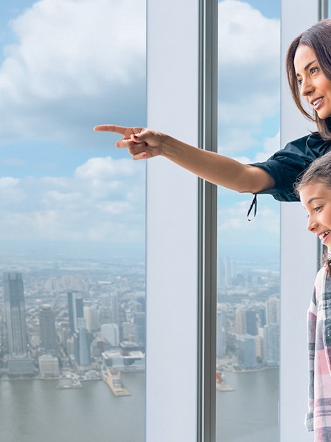Tourists enjoying New York City skyline from One World Observatory's 100th-floor deck.