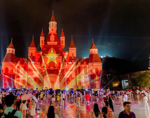 Castle at Vinpearl illuminated during TATA show, Nha Trang, with crowd gathered.