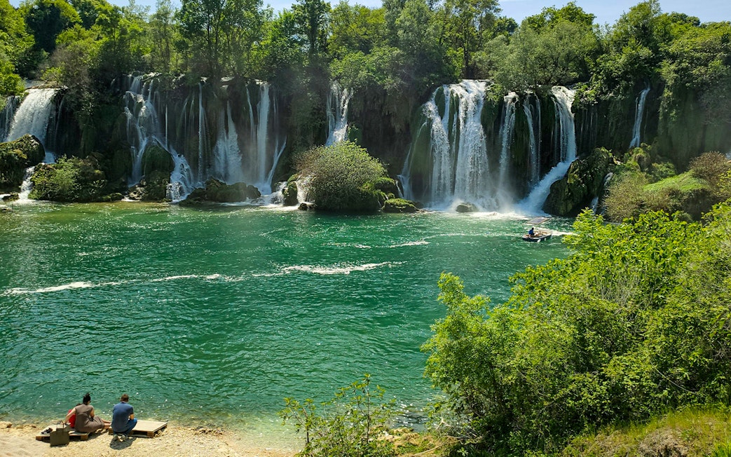Tourists enjoying a picnic by Kravica Waterfalls in Bosnia and Herzegovina.