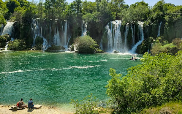 Tourists enjoying a picnic by Kravica Waterfalls in Bosnia and Herzegovina.