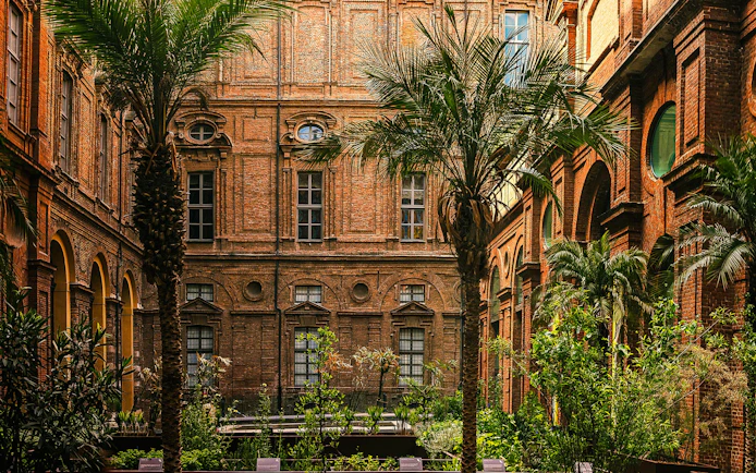 Egyptian Garden at the Egyptian Museum in Turin, Italy, with palm trees and historic architecture.