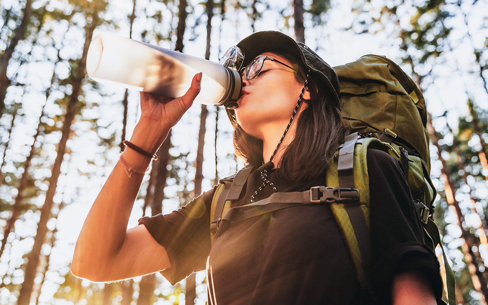 Tourist drinking water from a bottle in front of the Eiffel Tower, Paris, emphasizing hydration.