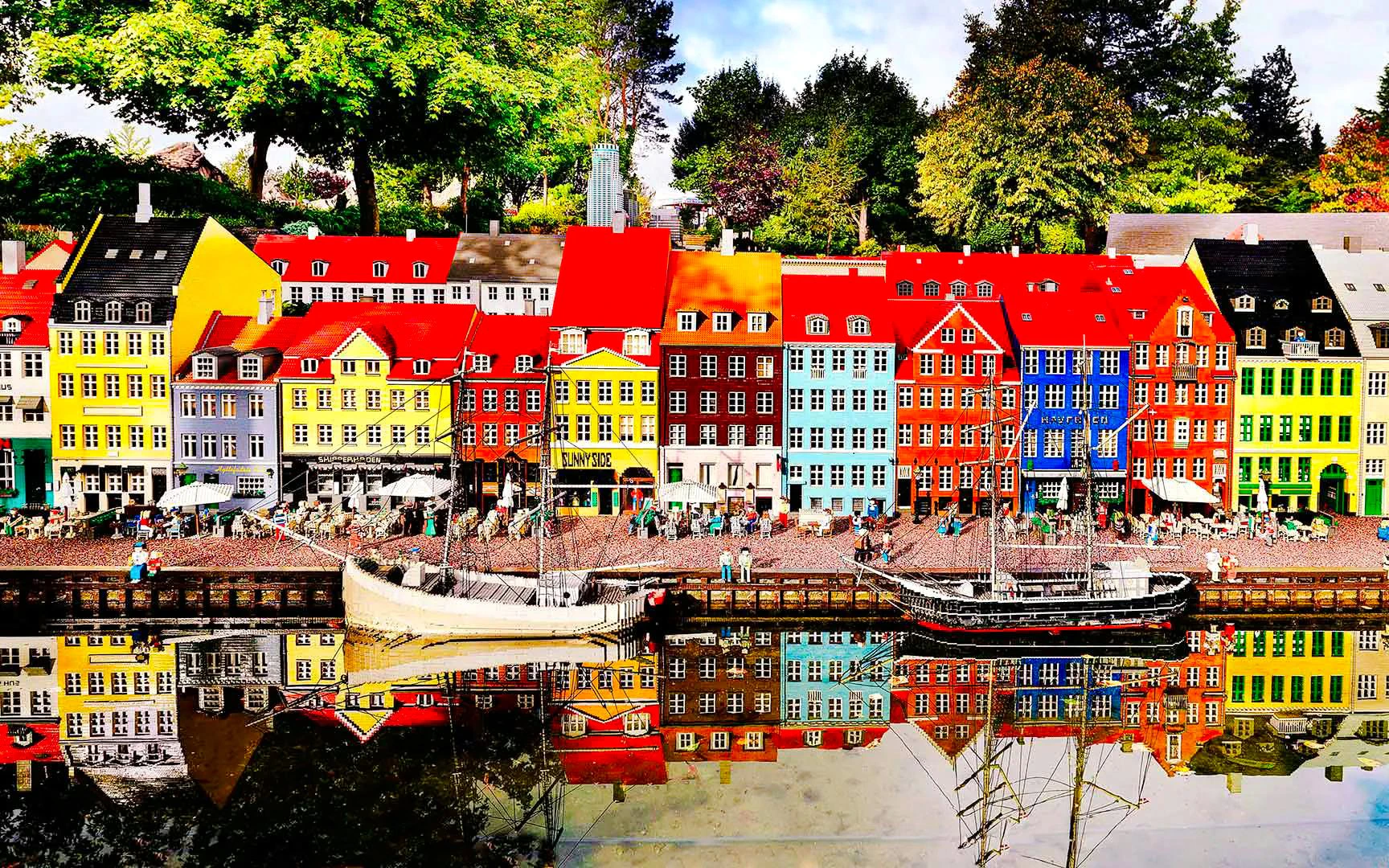 Colorful LEGO buildings and boats at LEGOLAND Miniland reflecting in water.