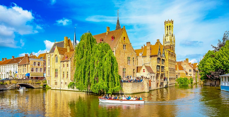 Canal cruise boat passing historic buildings in old town Brugge.