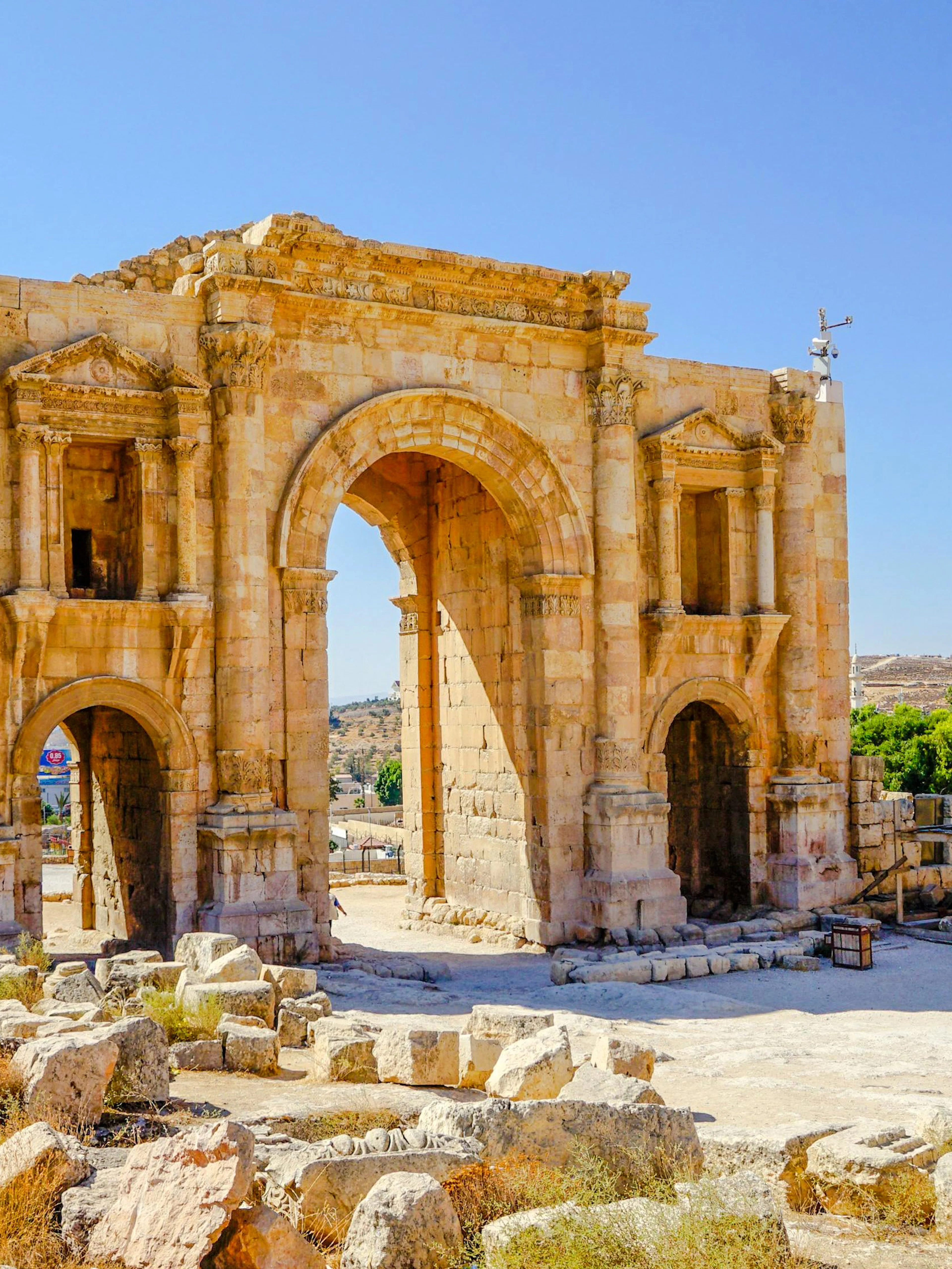Hadrian's Arch in Jerash, Jordan, with ancient stone ruins in the foreground.