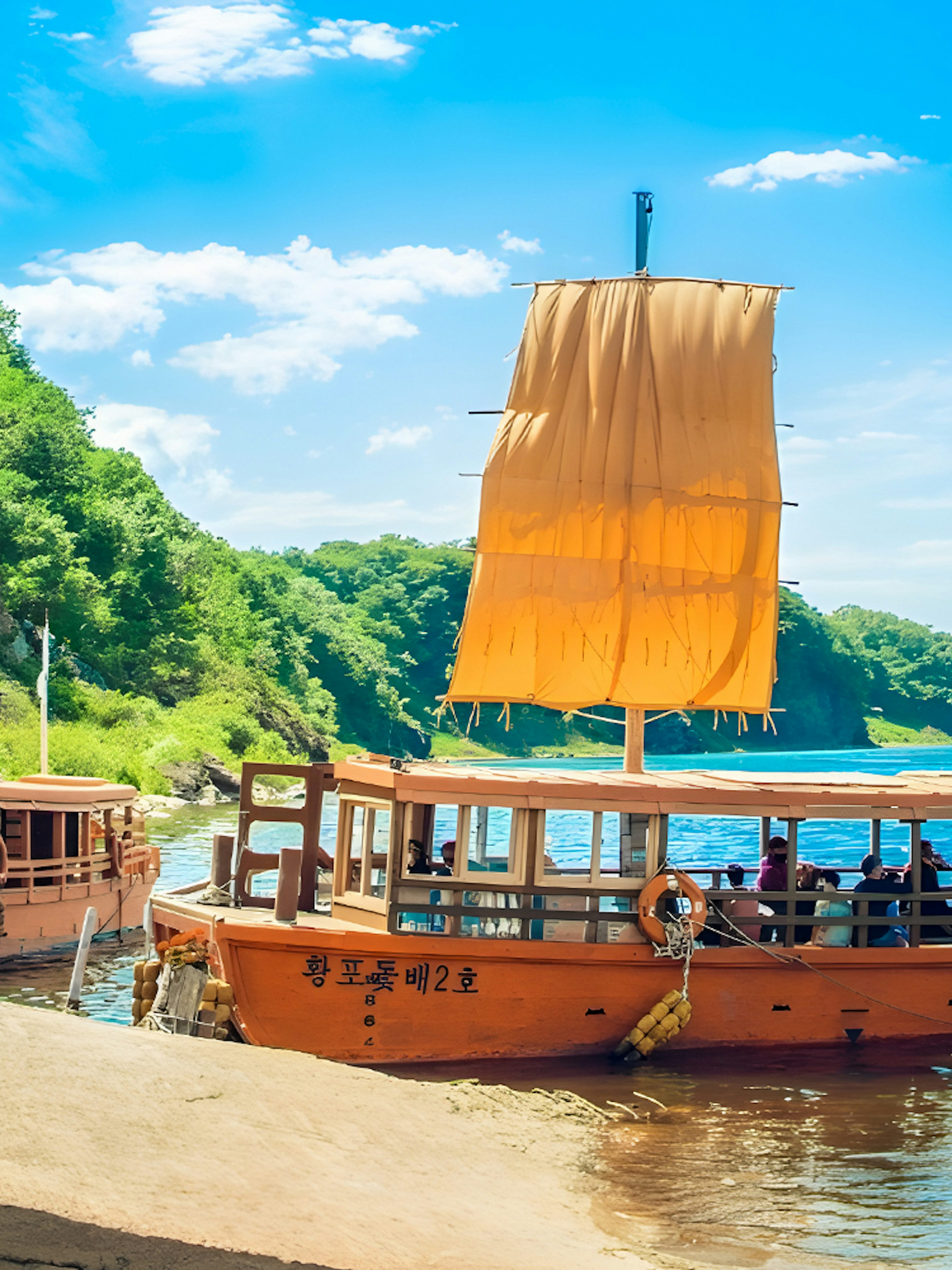 Traditional boats with orange sails docked by a river in a lush green landscape, DMZ tour.