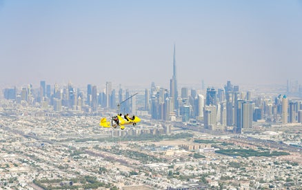 Gyrocopter flying over Dubai skyline near Burj Khalifa at Skydive Dubai Palm Drop Zone.