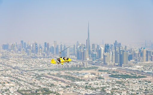 Gyrocopter flying over Dubai skyline near Burj Khalifa at Skydive Dubai Palm Drop Zone.