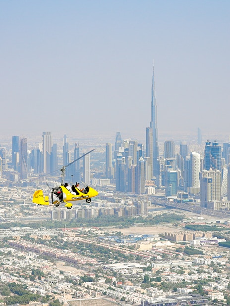 Gyrocopter flying over Dubai skyline near Burj Khalifa at Skydive Dubai Palm Drop Zone.