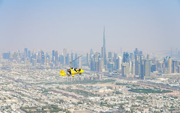 Gyrocopter flying over Dubai skyline near Burj Khalifa at Skydive Dubai Palm Drop Zone.