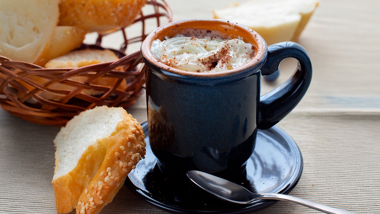 Hot chocolate and baguette on a Parisian café table.