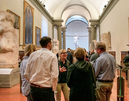 Tour group with guide in Accademia Gallery, Florence, viewing Michelangelo's David.