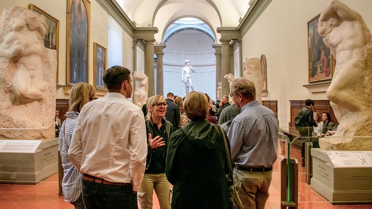 Tour group with guide in Accademia Gallery, Florence, viewing Michelangelo's David.
