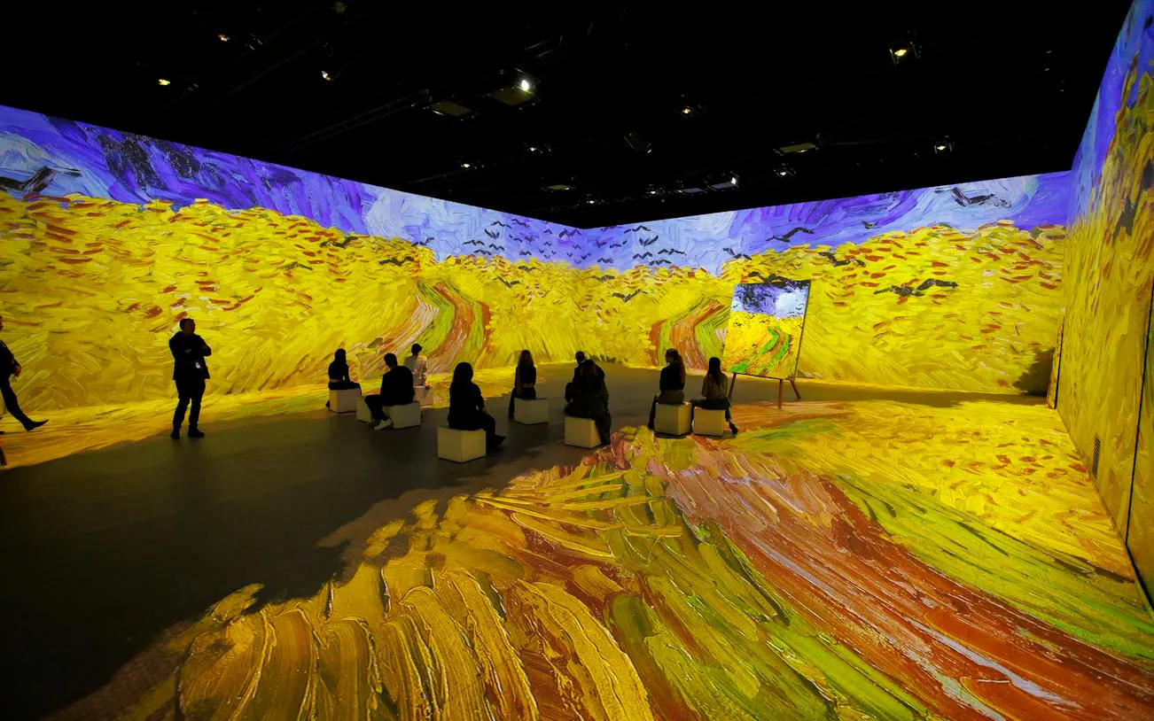 Visitors seated in Van Gogh immersive exhibit, Zurich, with vibrant wheat field projections.