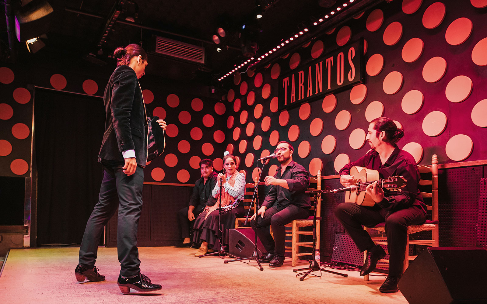 Flamenco artist performing on stage at Los Tarantos Flamenco Show with musicians.
