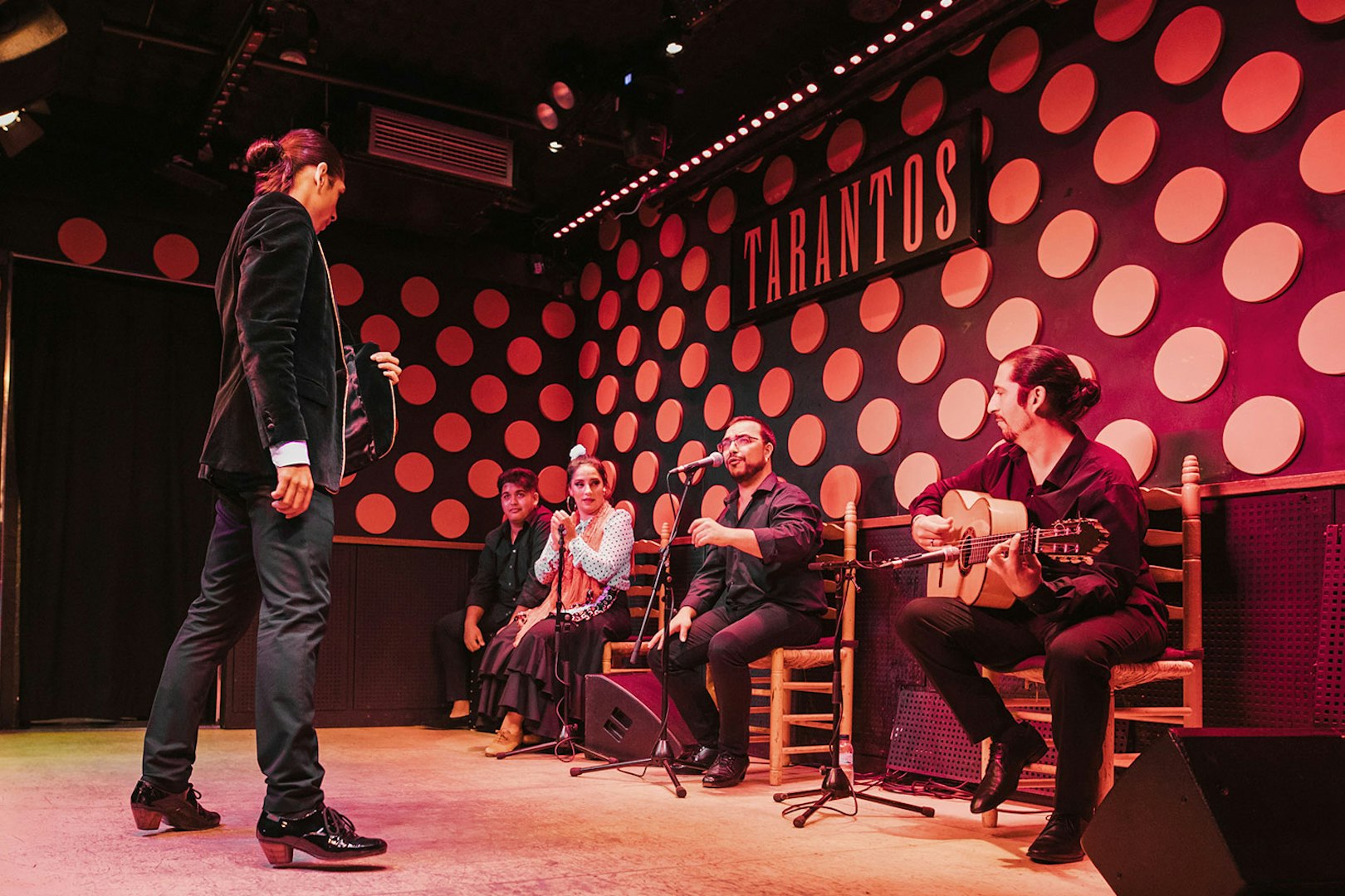 Flamenco artist performing on stage at Los Tarantos Flamenco Show with musicians.