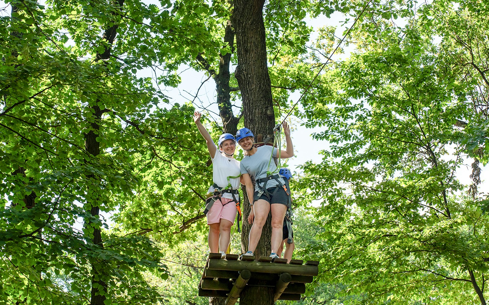 Women preparing to zipline at Hanuman World Phuket platform, surrounded by lush greenery.