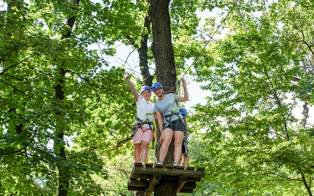 Women on zipline platform at Hanuman World Phuket surrounded by trees.