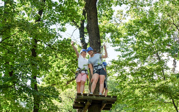 Women on zipline platform at Hanuman World Phuket surrounded by trees.