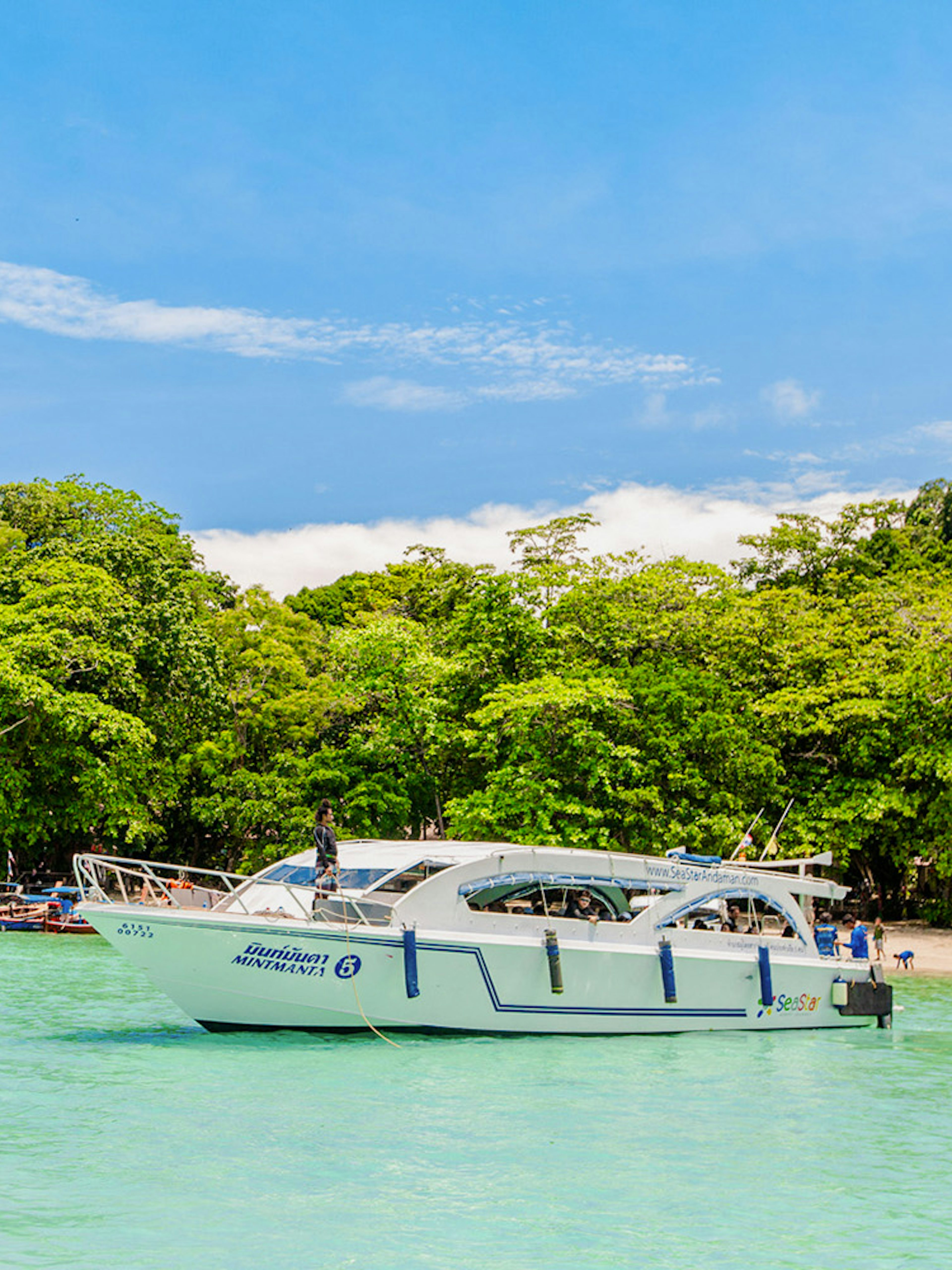 Speedboat near lush green Surin Islands shoreline, Thailand.