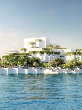 Aerial view of National History Museum Abu Dhabi with tiered white structures and greenery by the water.