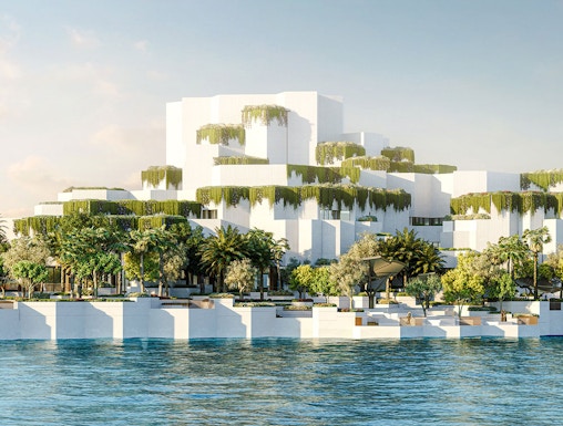Aerial view of National History Museum Abu Dhabi with tiered white structures and greenery by the water.