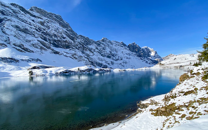 Snow-covered mountains and frozen lake at Trübsee during winter, view from Lucerne tour.