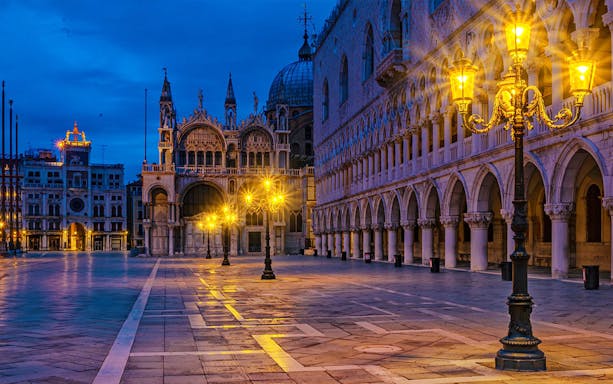 St. Mark's Basilica and square illuminated at night, Venice, during guided sunset tour.