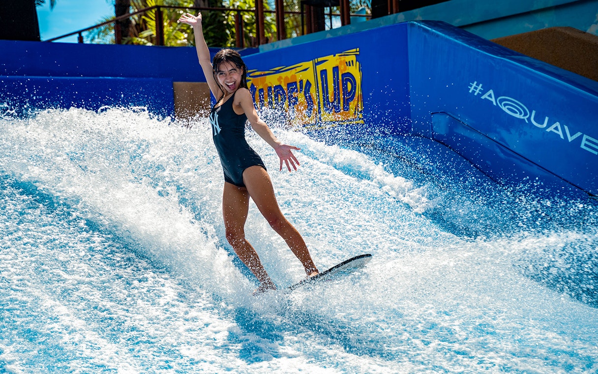 Person surfing on artificial wave at Columbia Pictures Aquaverse Pattaya.