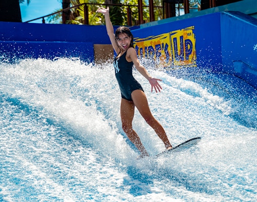 Person surfing on artificial wave at Columbia Pictures Aquaverse Pattaya.