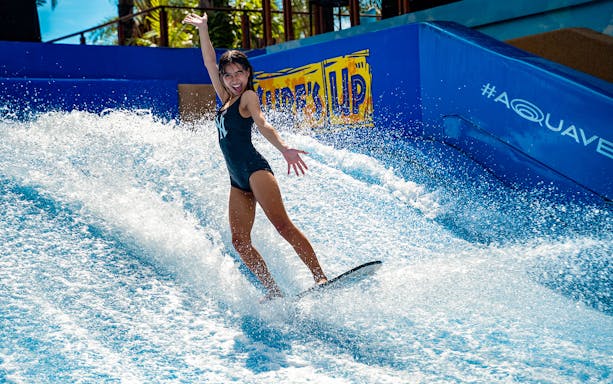 Person surfing on artificial wave at Columbia Pictures Aquaverse Pattaya.