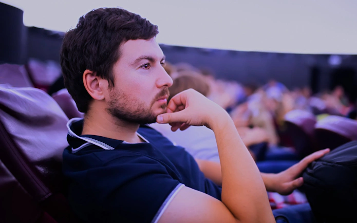 Man seated inside a planetarium, observing a celestial show.
