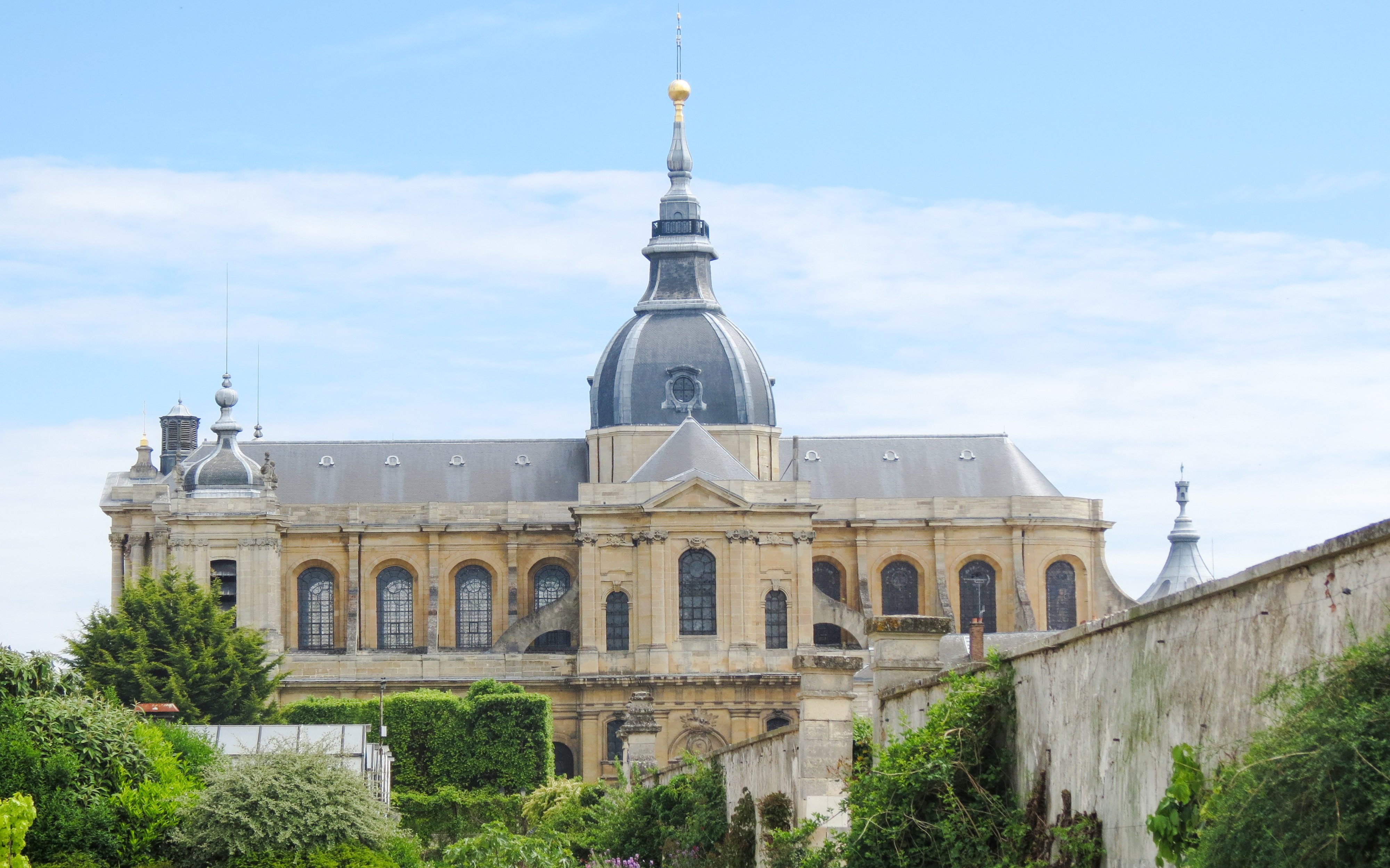 Historic building view from Potager du Roi, Versailles, with lush greenery in the foreground.