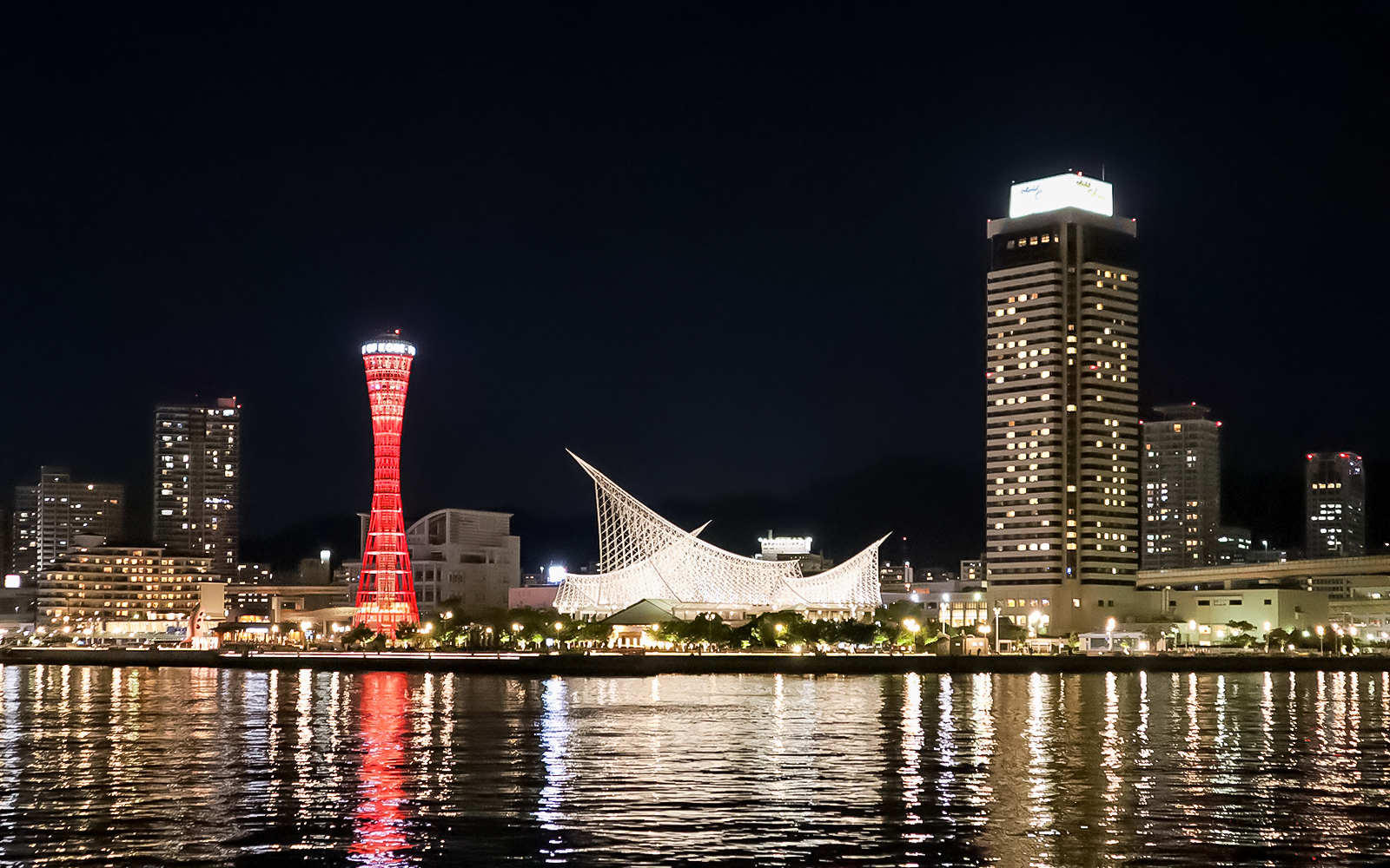 Kobe Port Tower illuminated at night with city skyline.