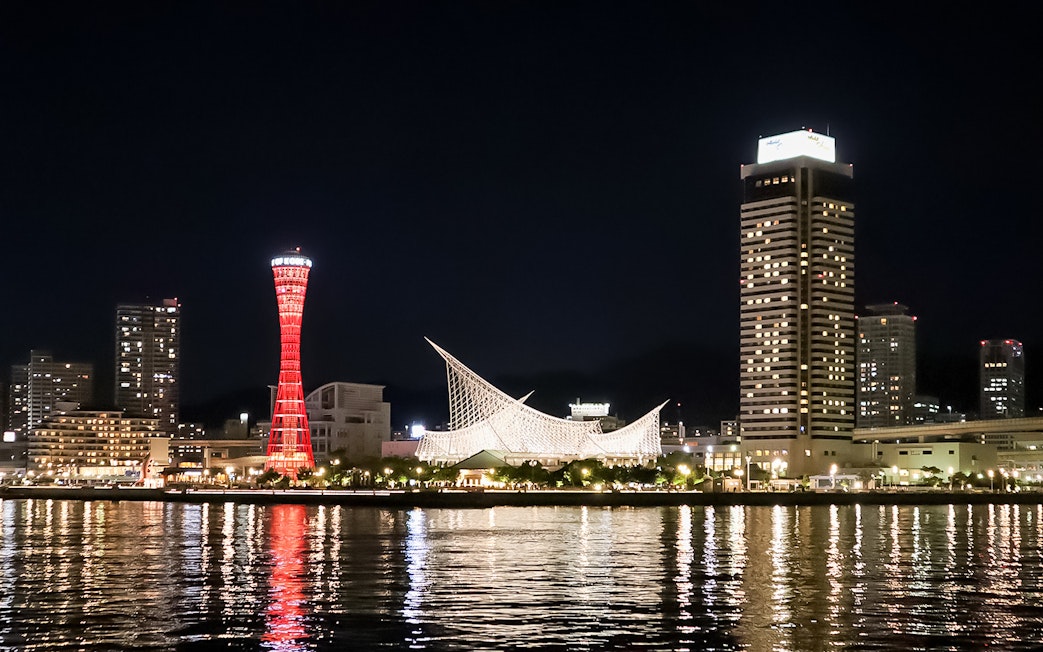 Kobe Port Tower illuminated at night with city skyline.