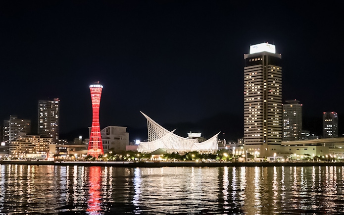Kobe Port Tower illuminated at night with city skyline.