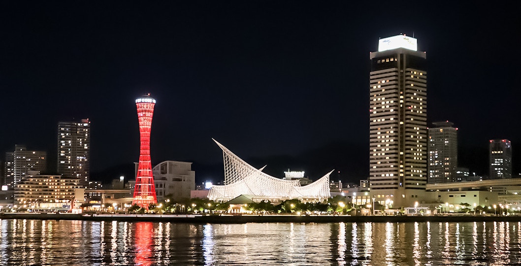 Kobe Port Tower illuminated at night with city skyline.