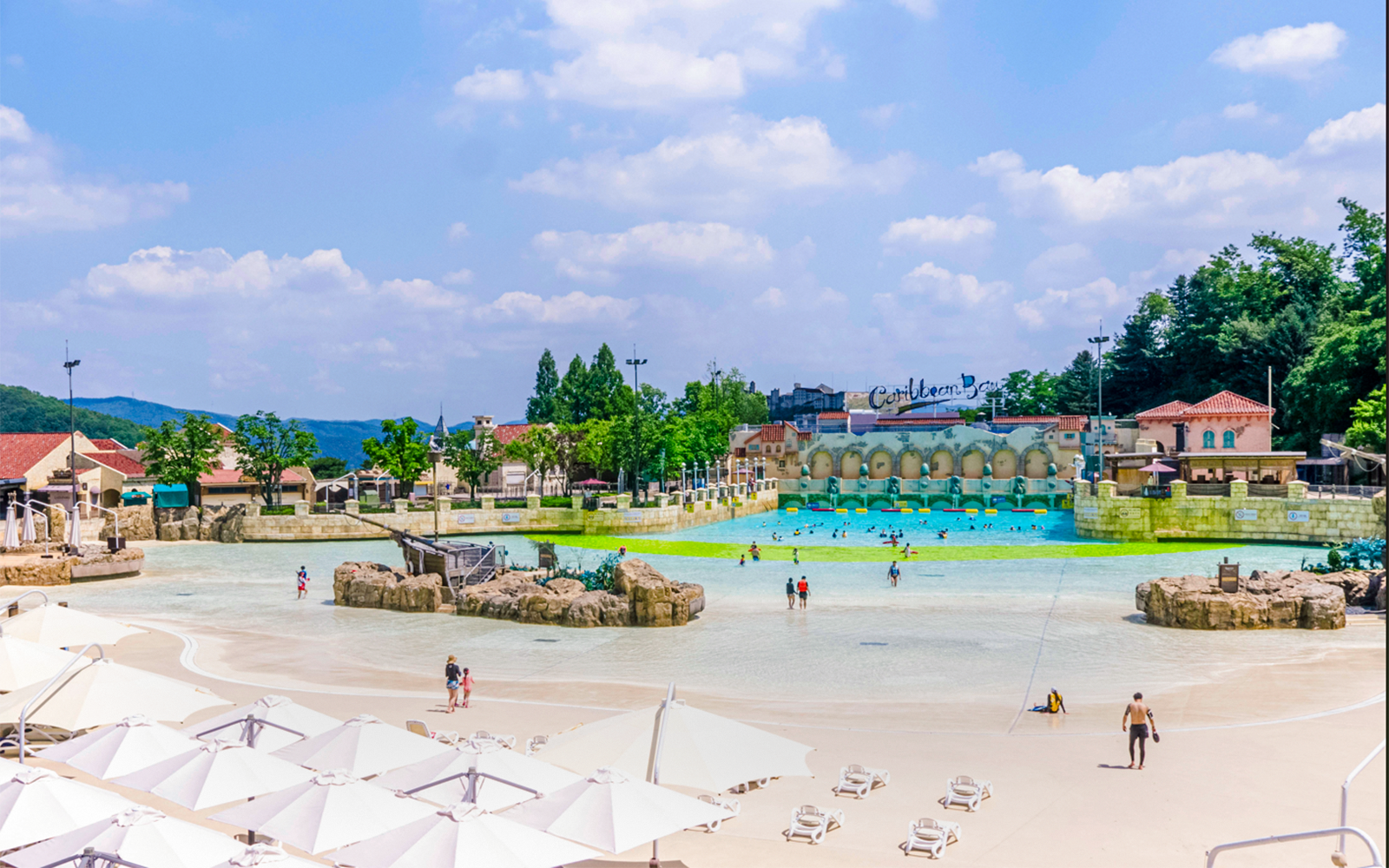 Tourists at Caribbean Bay Water Park enjoying the wave pool and sunbathing area.