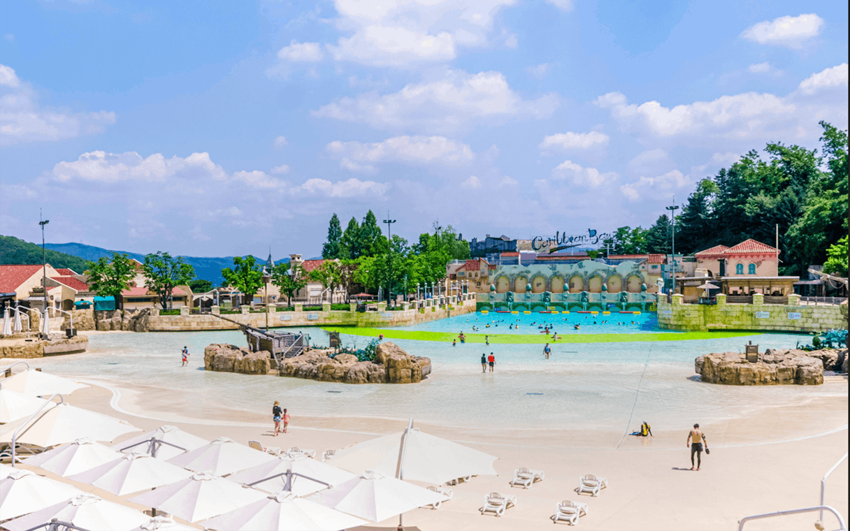 Tourists at Caribbean Bay Water Park enjoying the wave pool and sunbathing area.