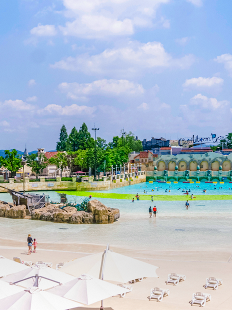 Tourists at Caribbean Bay Water Park enjoying the wave pool and sunbathing area.