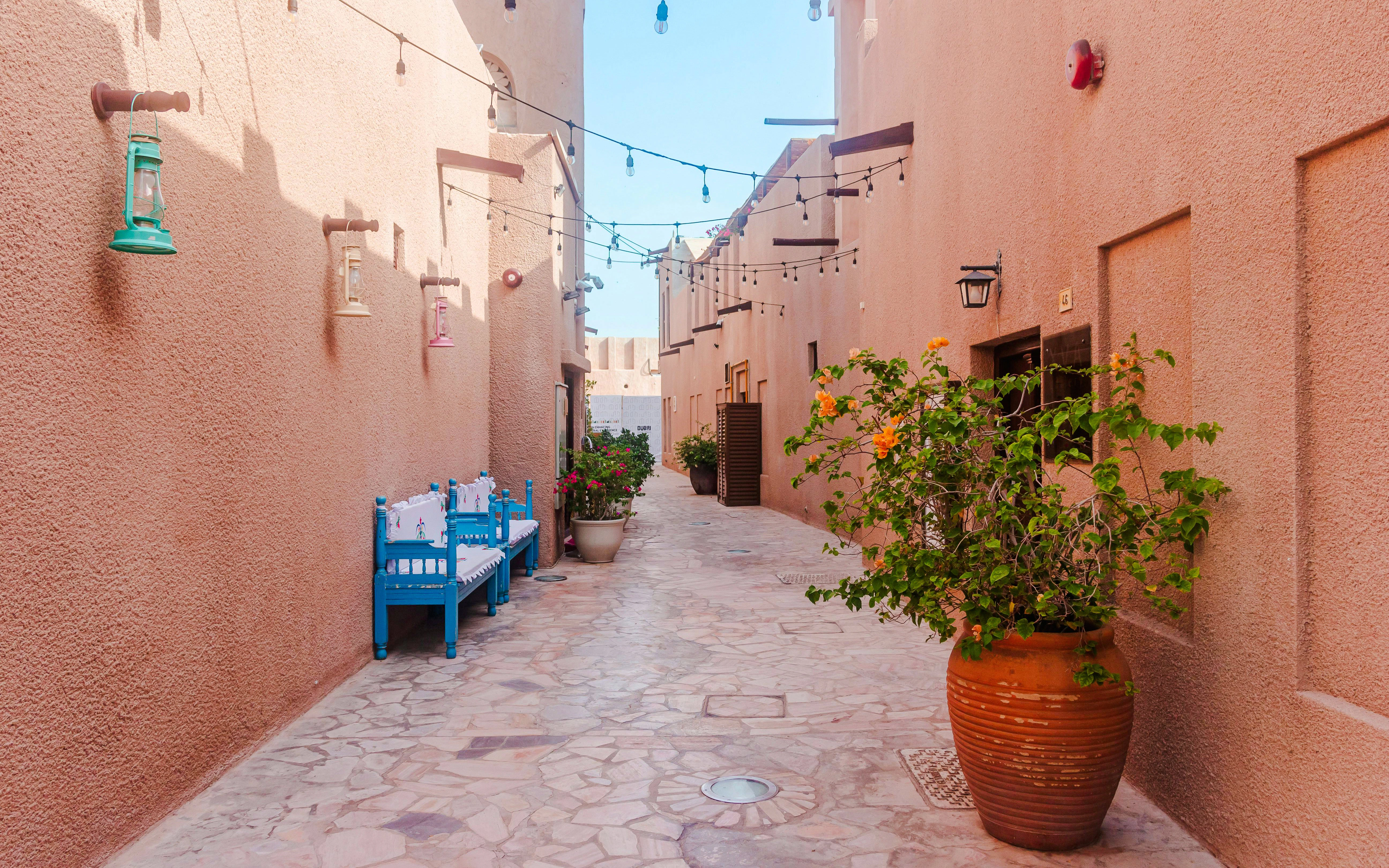 Narrow alley in Al Seef Heritage Souq with traditional lanterns and benches.