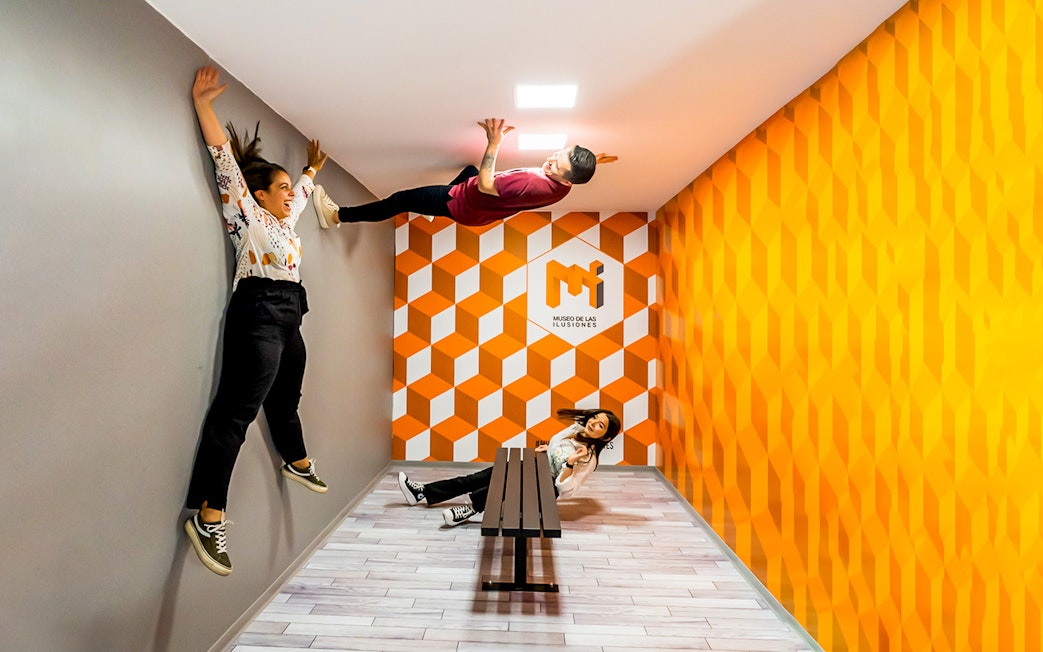 Visitors experiencing anti-gravity room at Museum of Illusions Seville.