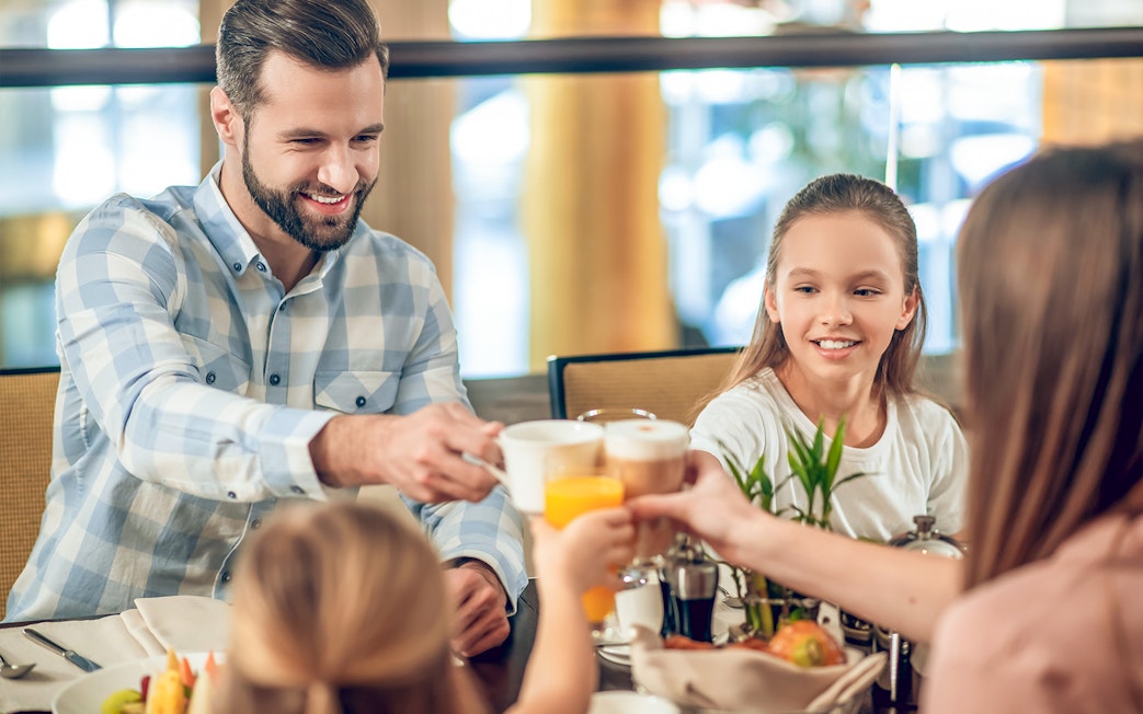 Family enjoying breakfast at Brasserie Rosalie, toasting with coffee and juice.